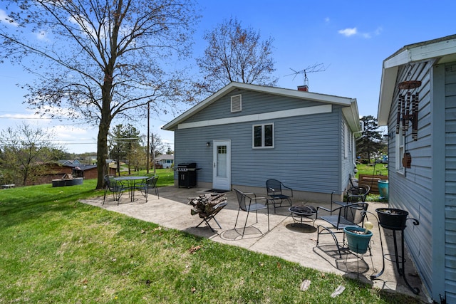 rear view of house featuring a lawn, a patio, and a fire pit