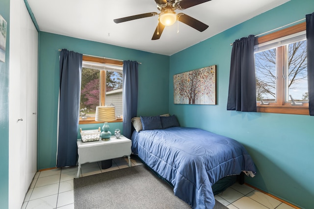 bedroom featuring ceiling fan, light tile patterned floors, and multiple windows