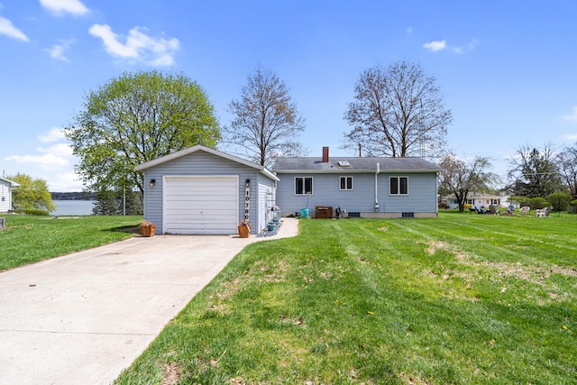 back of house featuring a garage, a water view, a chimney, a yard, and driveway