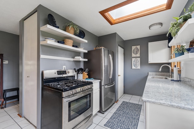 kitchen featuring white cabinets, open shelves, appliances with stainless steel finishes, a sink, and a skylight