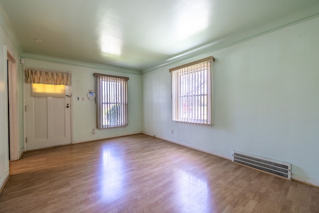 empty room with light wood-style flooring, baseboards, and visible vents