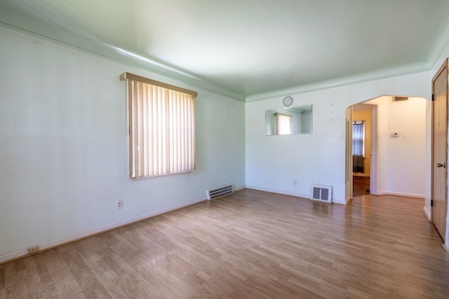 19302 Moross Rd, Detroit, MI 48224 - empty room featuring arched walkways, wood finished floors, and baseboards
