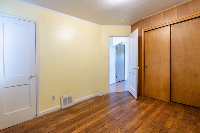 19302 Moross Rd, Detroit, MI 48224 - unfurnished bedroom featuring hardwood / wood-style floors, a closet, baseboards, and ornamental molding