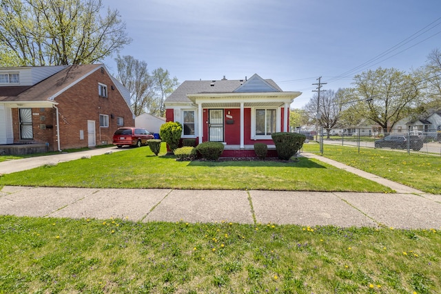 view of front of property featuring covered porch, brick siding, fence, and a front yard