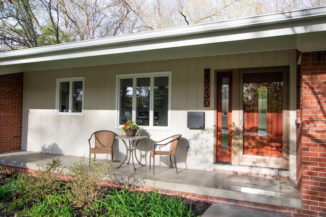 doorway to property with brick siding and covered porch