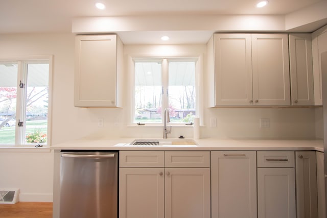 kitchen with a sink, a healthy amount of sunlight, light countertops, and dishwasher