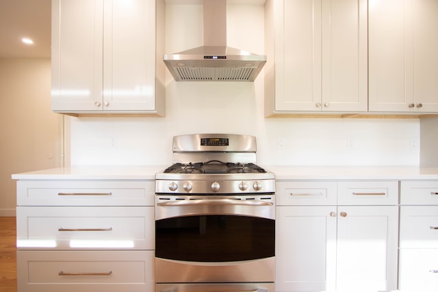 kitchen with stainless steel range with gas stovetop, light countertops, and wall chimney exhaust hood