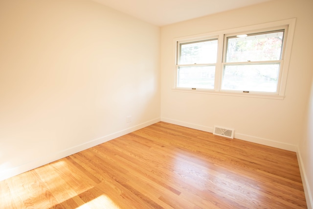 spare room featuring light wood-style floors, baseboards, and visible vents