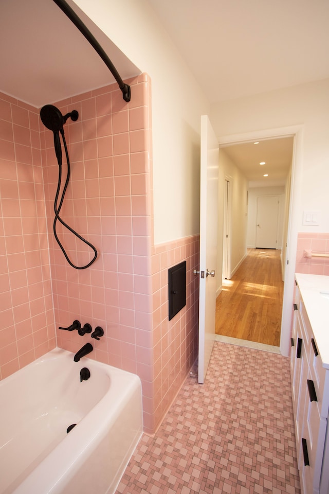 bathroom featuring vanity, tile walls, bathtub / shower combination, a wainscoted wall, and tile patterned floors