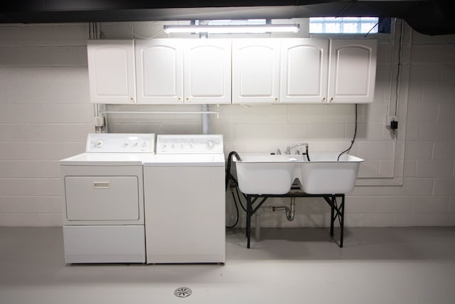 laundry area featuring separate washer and dryer, a sink, cabinet space, and concrete block wall
