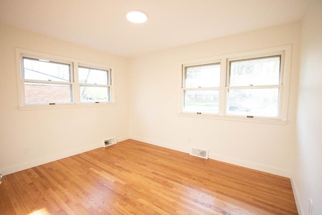 unfurnished room with baseboards, visible vents, and light wood-type flooring