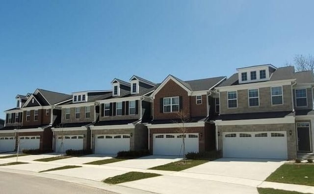multi unit property featuring an attached garage, driveway, and stone siding