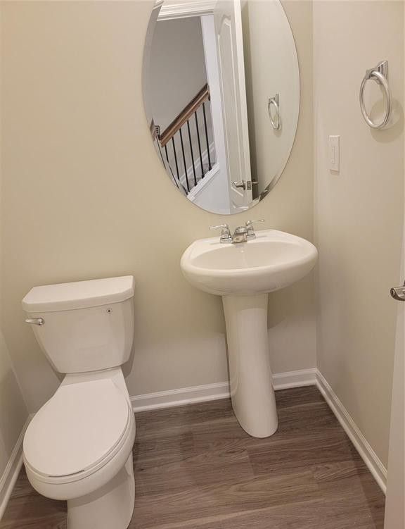 bathroom with baseboards, toilet, and wood finished floors