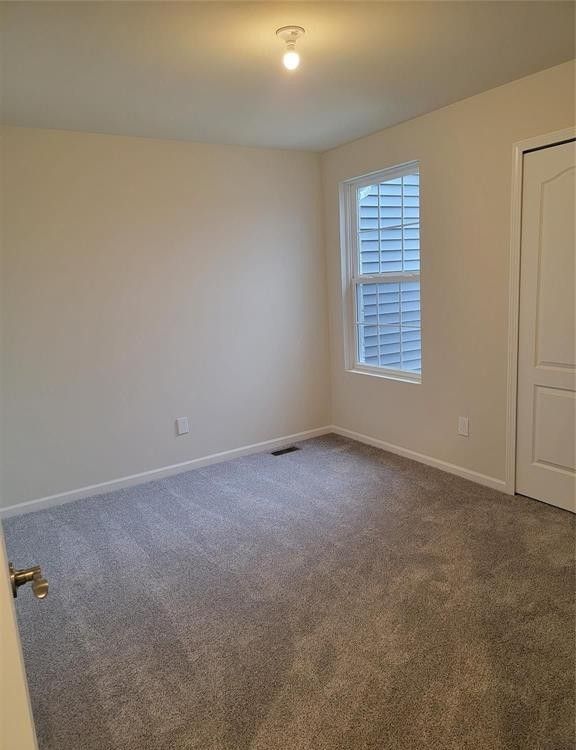 spare room featuring carpet floors, baseboards, and visible vents