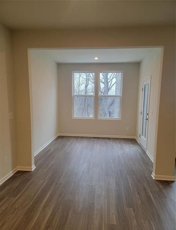 empty room featuring baseboards and dark wood-style floors
