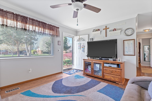 living area with crown molding, a ceiling fan, baseboards, wood finished floors, and visible vents