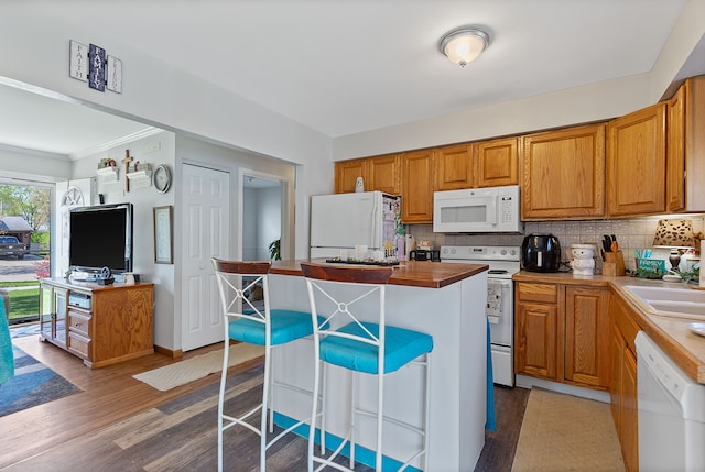 kitchen with white appliances, a kitchen island, wood finished floors, and tasteful backsplash