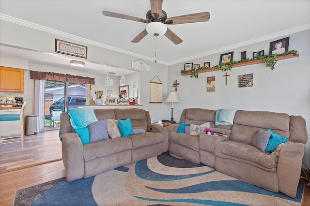 living room with light wood-style floors, ornamental molding, and a ceiling fan