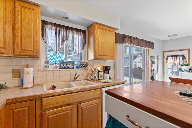 kitchen with a sink, butcher block counters, backsplash, and brown cabinets