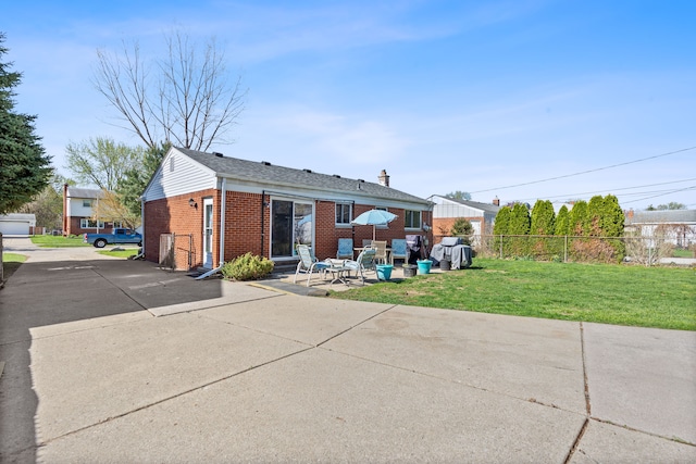 rear view of house with fence, brick siding, entry steps, a patio area, and a yard