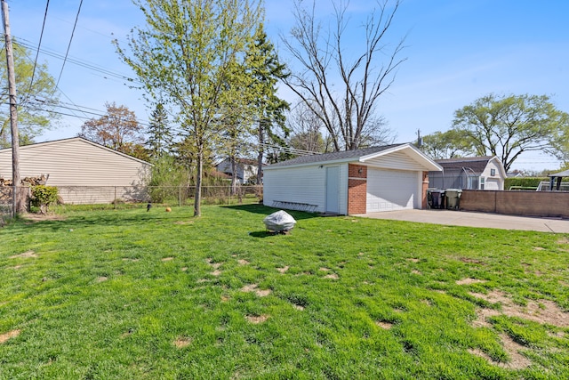 view of yard featuring a garage, fence, and an outbuilding