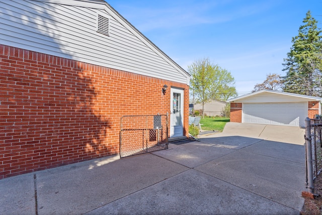 view of side of property with brick siding, an outdoor structure, and a detached garage