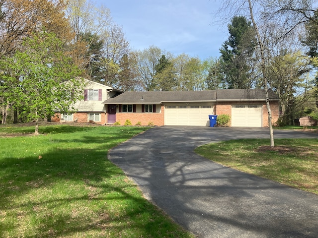 split level home featuring a garage, a front yard, driveway, and brick siding