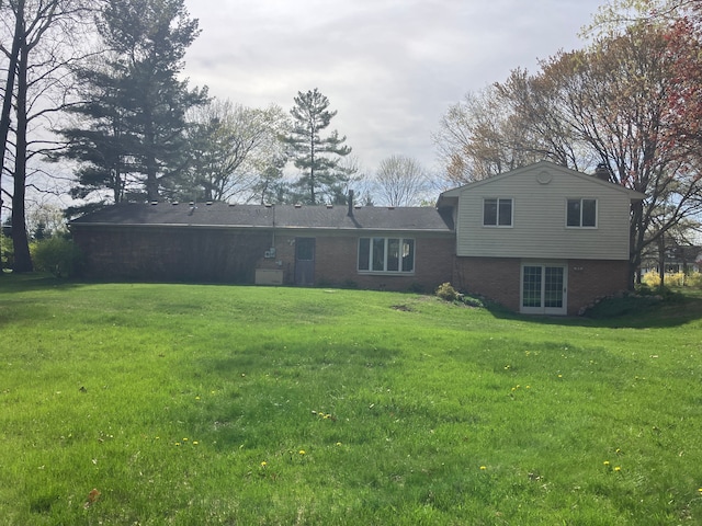 back of house with a lawn and brick siding