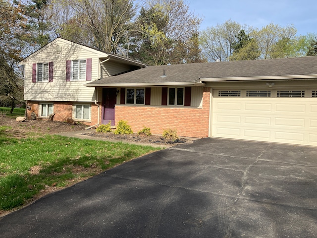 tri-level home featuring brick siding, an attached garage, and driveway