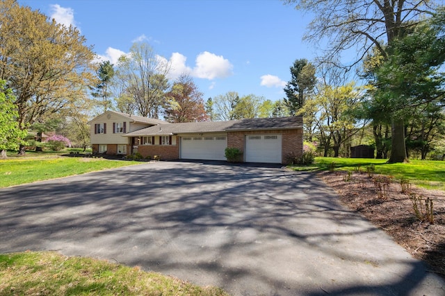 split level home with brick siding, an attached garage, a front lawn, and aphalt driveway