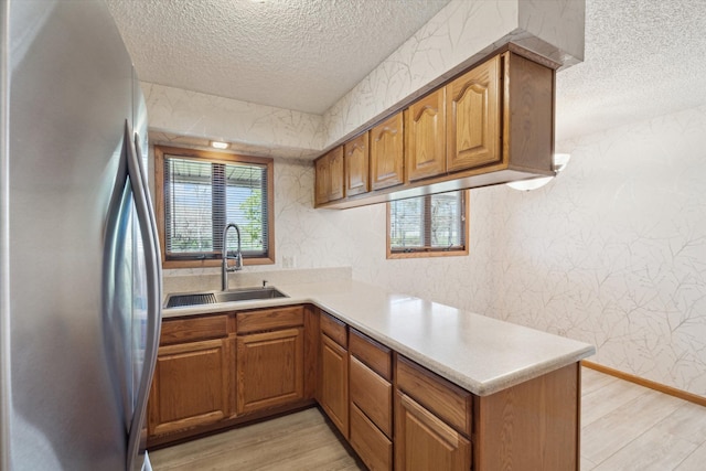 kitchen with light wood-style floors, freestanding refrigerator, a sink, and a textured ceiling