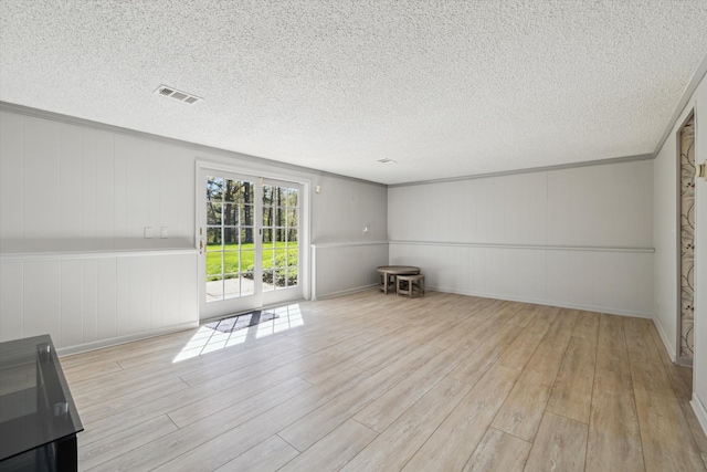 unfurnished room with a decorative wall, wood finished floors, and visible vents
