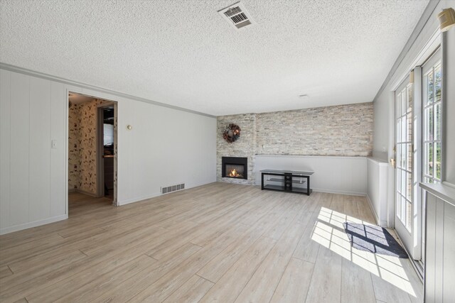 unfurnished living room with a textured ceiling, visible vents, and wood finished floors