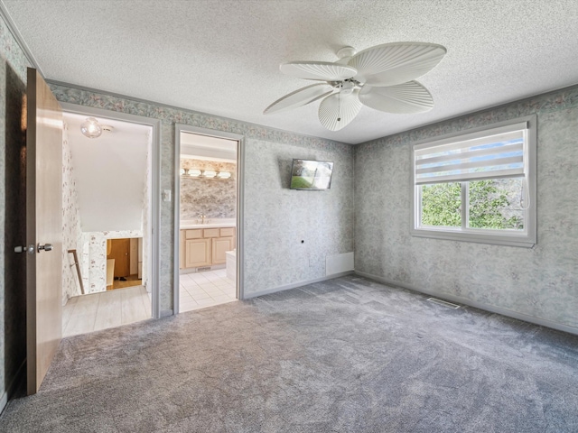 empty room featuring light carpet, wallpapered walls, and a textured ceiling