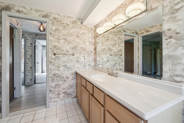 bathroom with vanity, tile patterned flooring, baseboards, and wallpapered walls