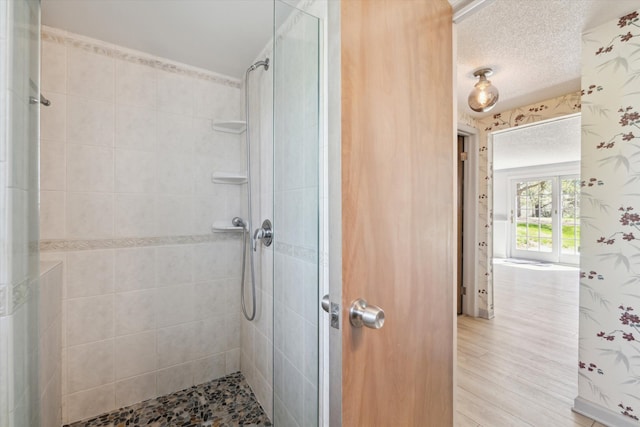full bath with a stall shower, a textured ceiling, and wood finished floors
