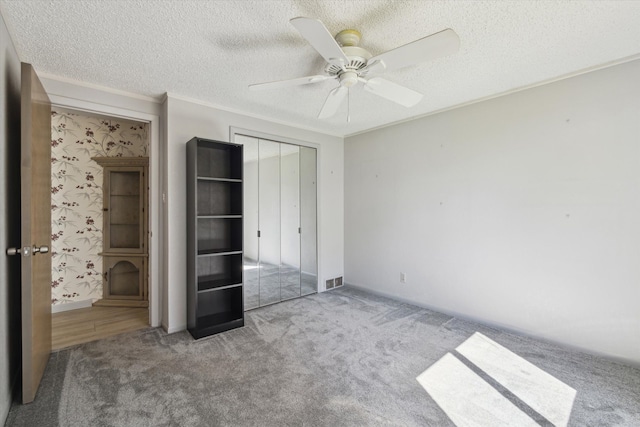 unfurnished bedroom featuring carpet floors, a textured ceiling, crown molding, and a closet