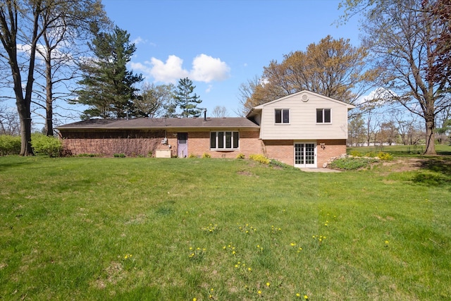 back of house featuring brick siding and a yard