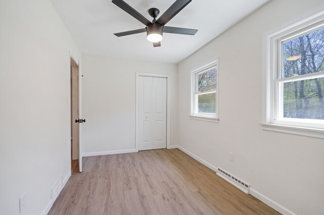 unfurnished bedroom featuring visible vents, light wood-style flooring, baseboards, and a closet