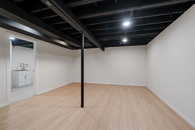 finished below grade area with baseboards, a sink, wood finished floors, and visible vents