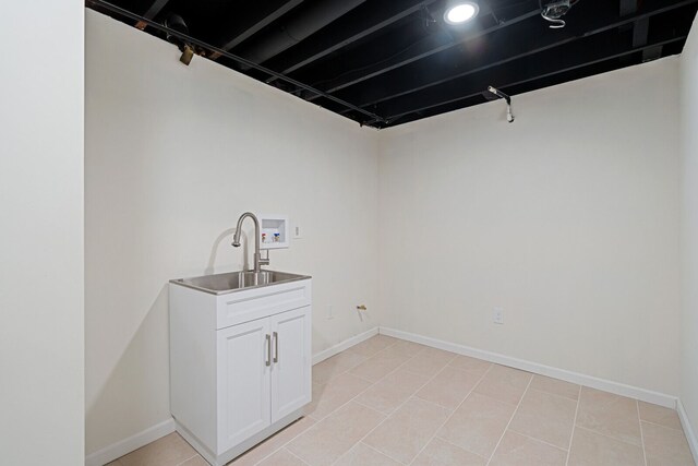 laundry area with a sink, baseboards, light tile patterned floors, and laundry area
