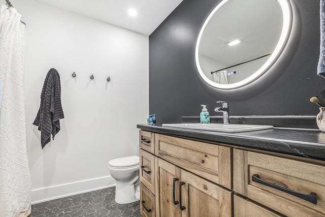 full bath featuring baseboards, vanity, and toilet
