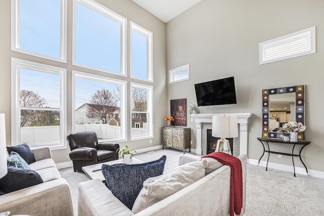 carpeted living room with baseboards, a wealth of natural light, and a towering ceiling