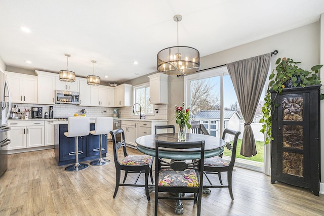 dining area with an inviting chandelier, recessed lighting, and light wood-style floors
