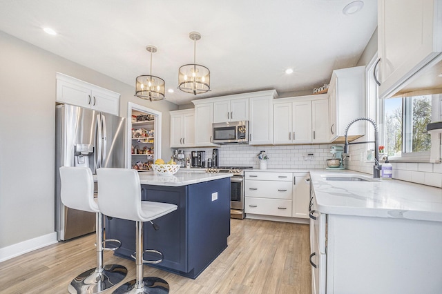 kitchen with decorative backsplash, a kitchen island, appliances with stainless steel finishes, a sink, and white cabinets