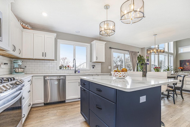 kitchen with a sink, appliances with stainless steel finishes, white cabinetry, and a notable chandelier