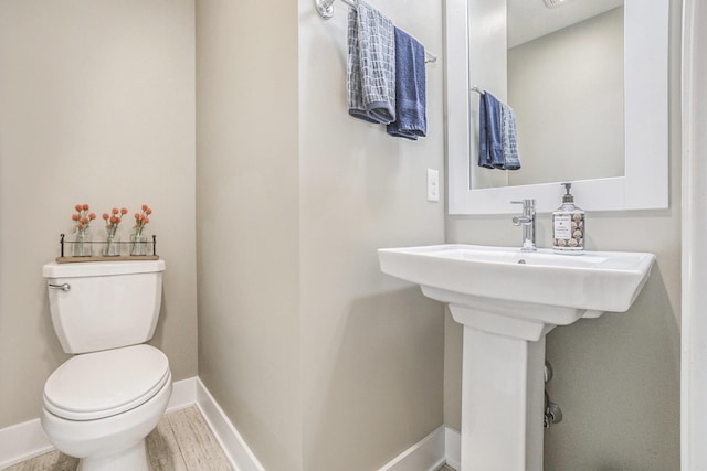 bathroom featuring toilet, baseboards, and wood finished floors