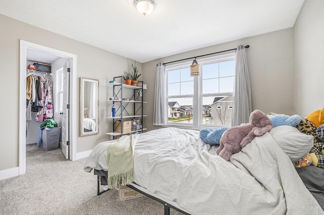 bedroom with carpet flooring, baseboards, a walk in closet, and a closet