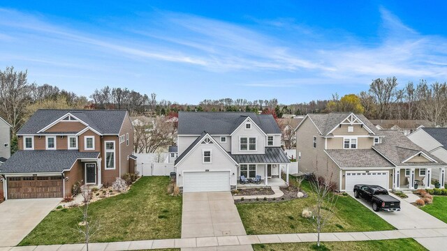 traditional home with covered porch, driveway, a residential view, fence, and a front lawn