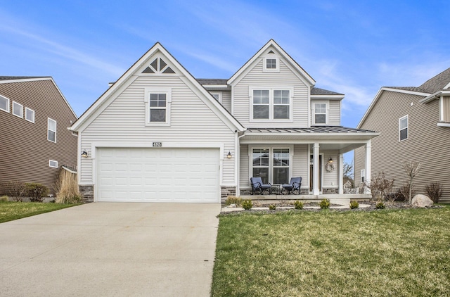 view of front of house featuring an attached garage, a front yard, a standing seam roof, concrete driveway, and a porch